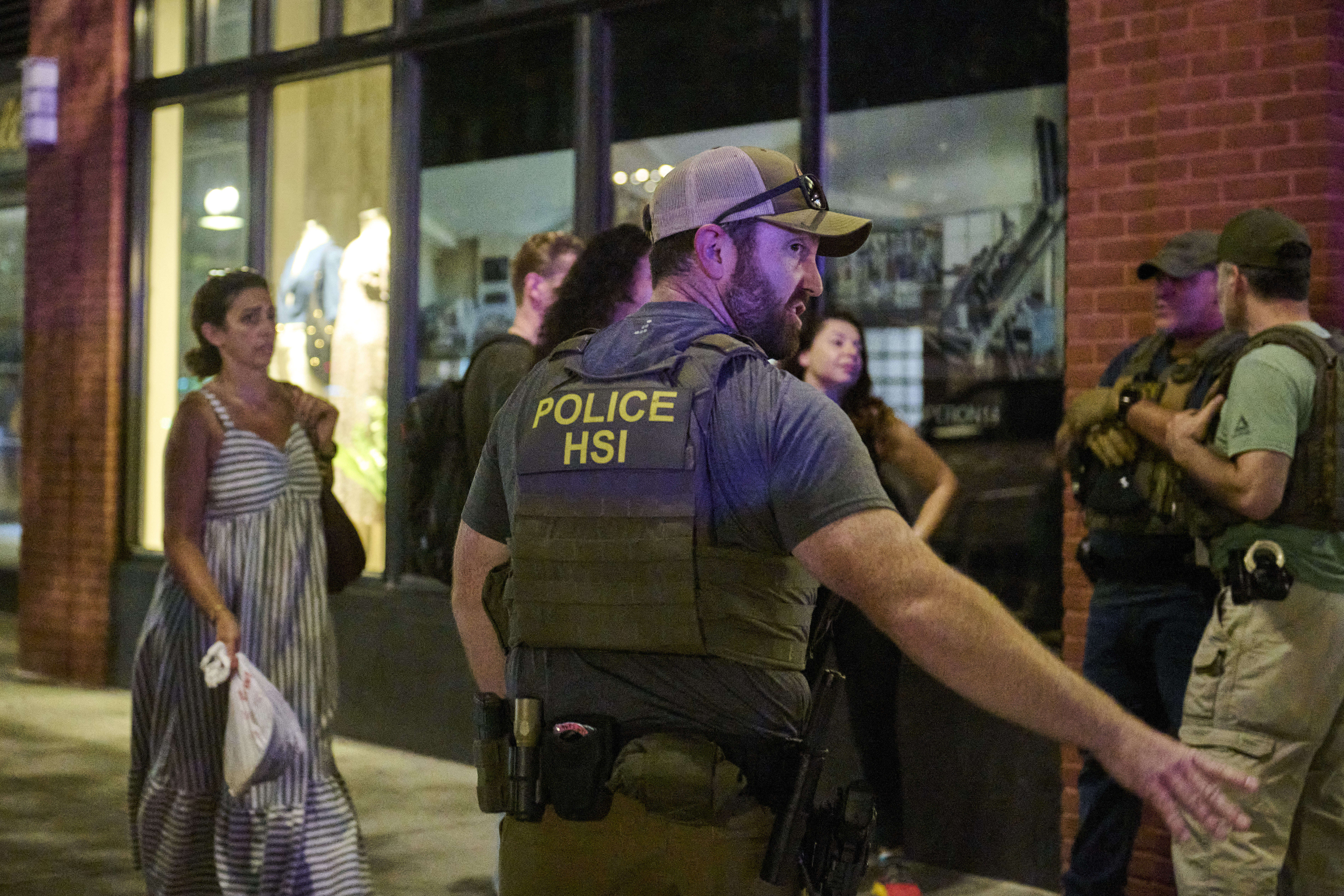 Officers stand on guard, as passersby look on warily.