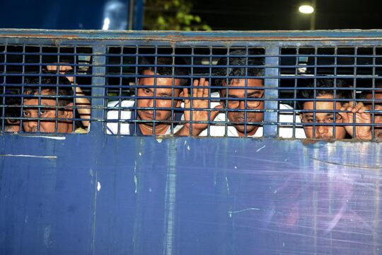 In Bangladesh, lawyers close to the government were allegedly involved in violence during student protests in the summer of 2024. Photo: Men are locked in a blue police van. Their faces are visible through the grilles in front of the windows.
