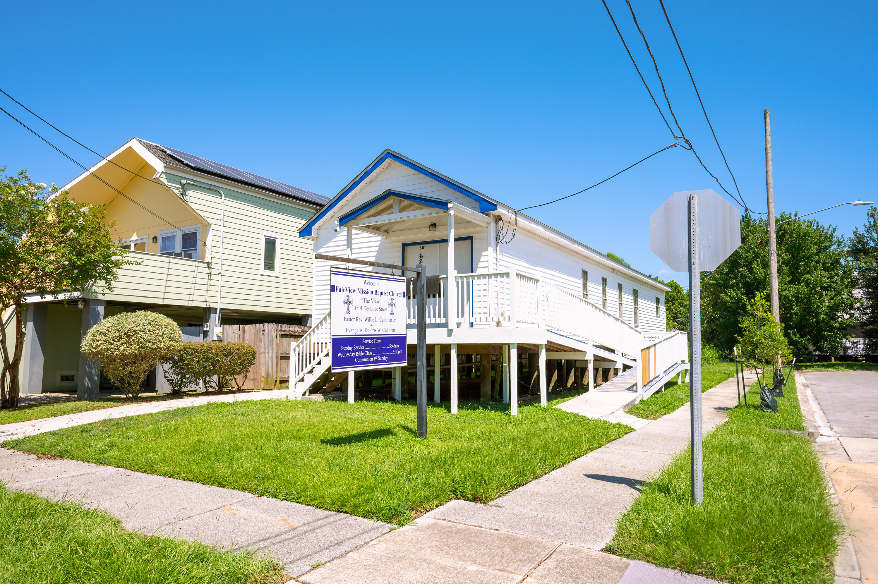 A single-story white building, which serves as a church, is raised on stilts. 
