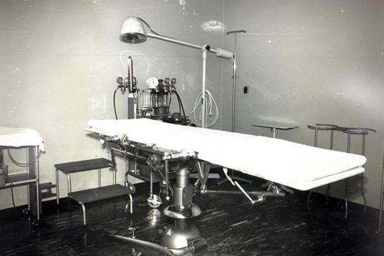Black and white photo of a hospital bed (operating table type) in the 60-70s.