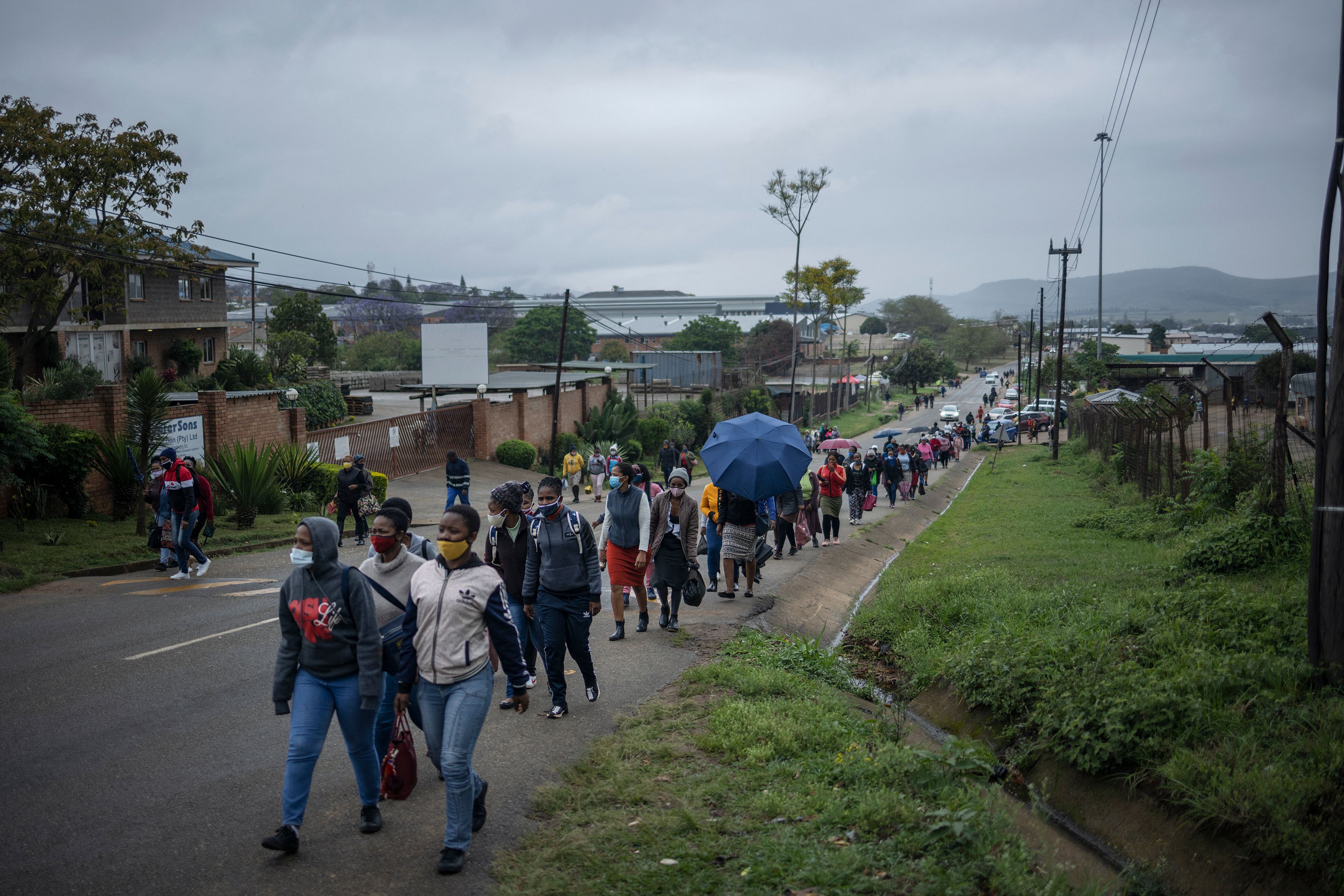 Line of people walking along the edge of a road.