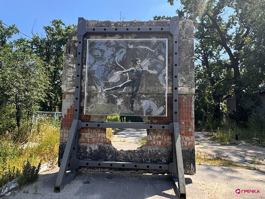 A work by the famous street artist Banksy is on display in Irpin, Ukraine. Photo: a gymnast is painted on a section of wall that is isolated and protected by glass. Below the gymnast is a large hole in the wall.