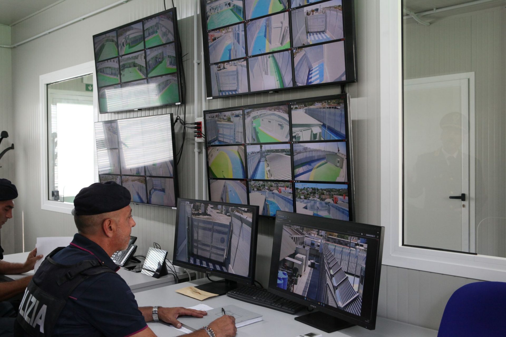 An Italian police officer sits in front of screens showing images from surveillance cameras in the Italian refugee arrival camp in the Albanian port city of Shengjin. An Italian Navy ship brought a second group of migrants from Egypt and Bangladesh picked up in the Mediterranean to its offshore asylum processing centre in Albania on Friday, despite a court challenge hanging over the new Italian scheme.